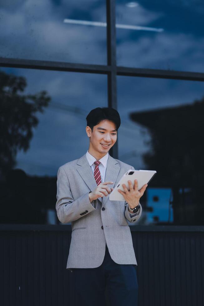 Serious businessman looking at paper documents in front of office building. Focused male manager checking reports before work while standing outdoors. photo