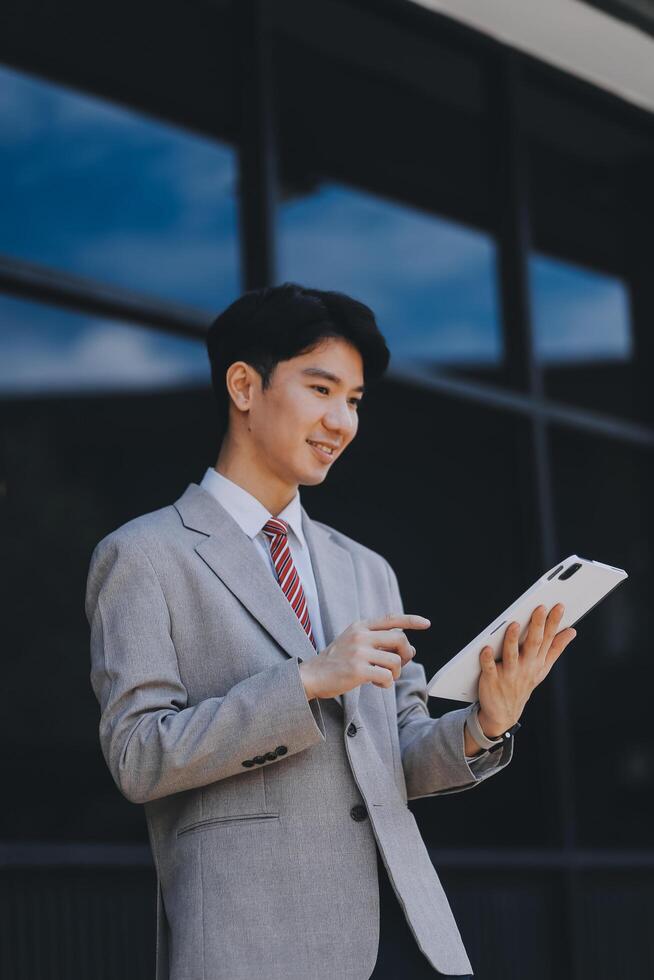 Serious businessman looking at paper documents in front of office building. Focused male manager checking reports before work while standing outdoors. photo