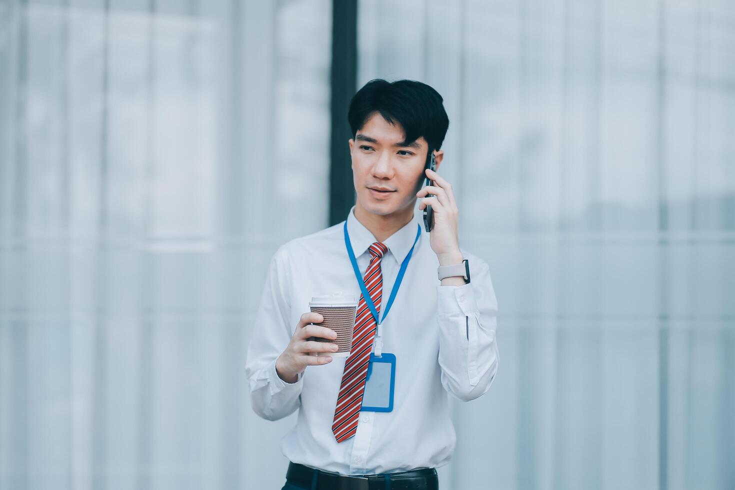 Happy businessman drinking coffee and using mobile phone in front of his office building. photo