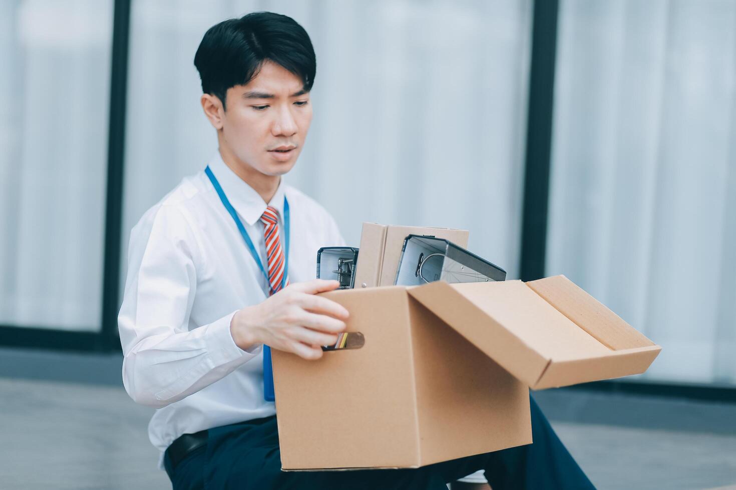 Sadness depressed Businessman with box cardboard packing personal items after losing jobs. Failure businessman sitting at stair front of building. Your fired Unemployed Jobless People Crisis photo