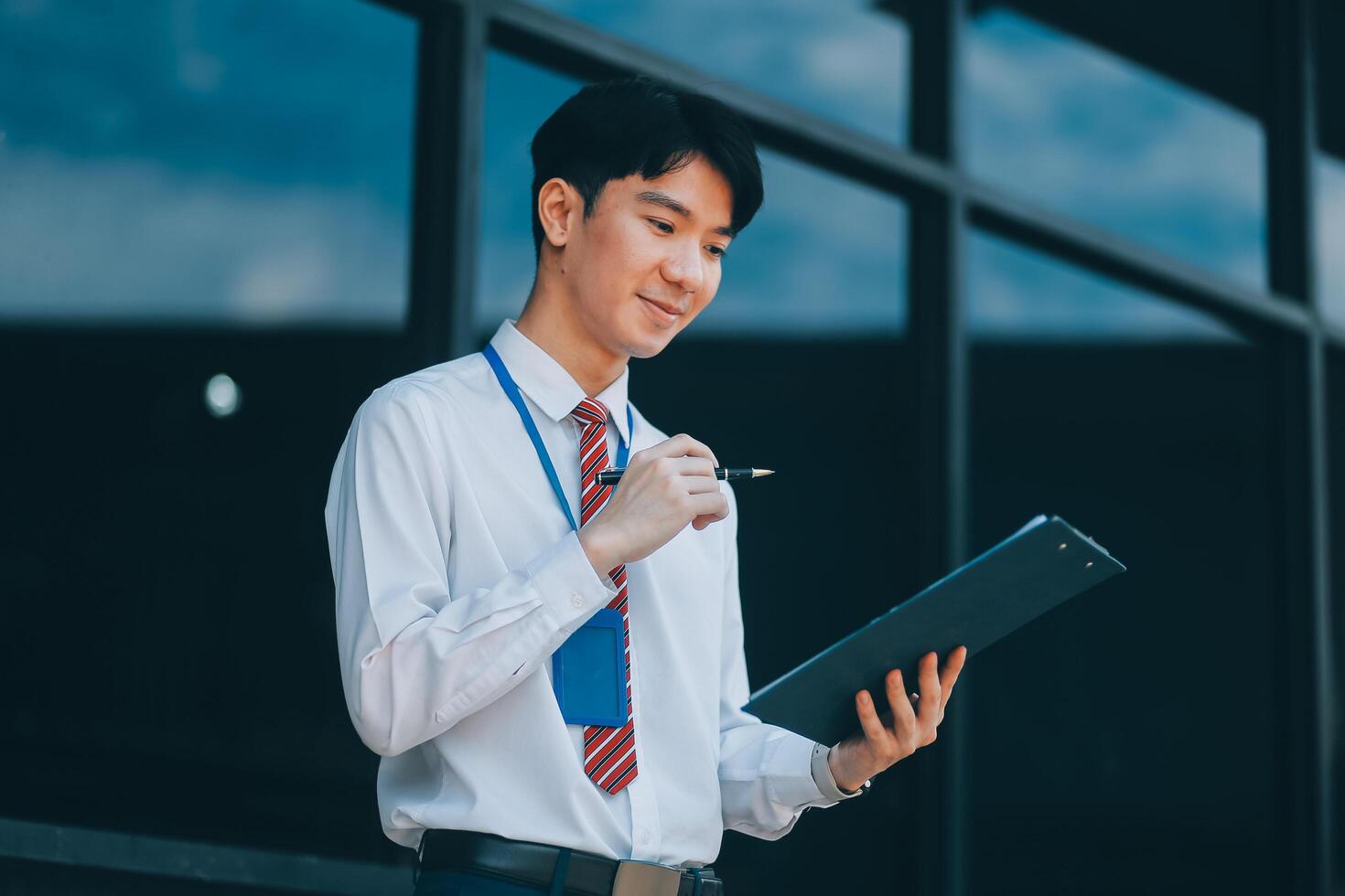 Serious businessman looking at paper documents in front of office building. Focused male manager checking reports before work while standing outdoors. photo