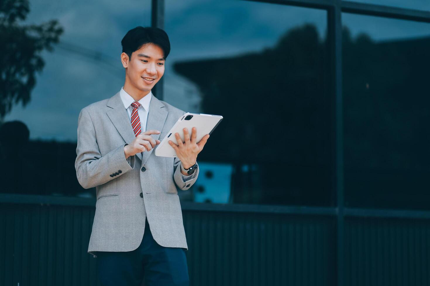 Serious businessman looking at paper documents in front of office building. Focused male manager checking reports before work while standing outdoors. photo