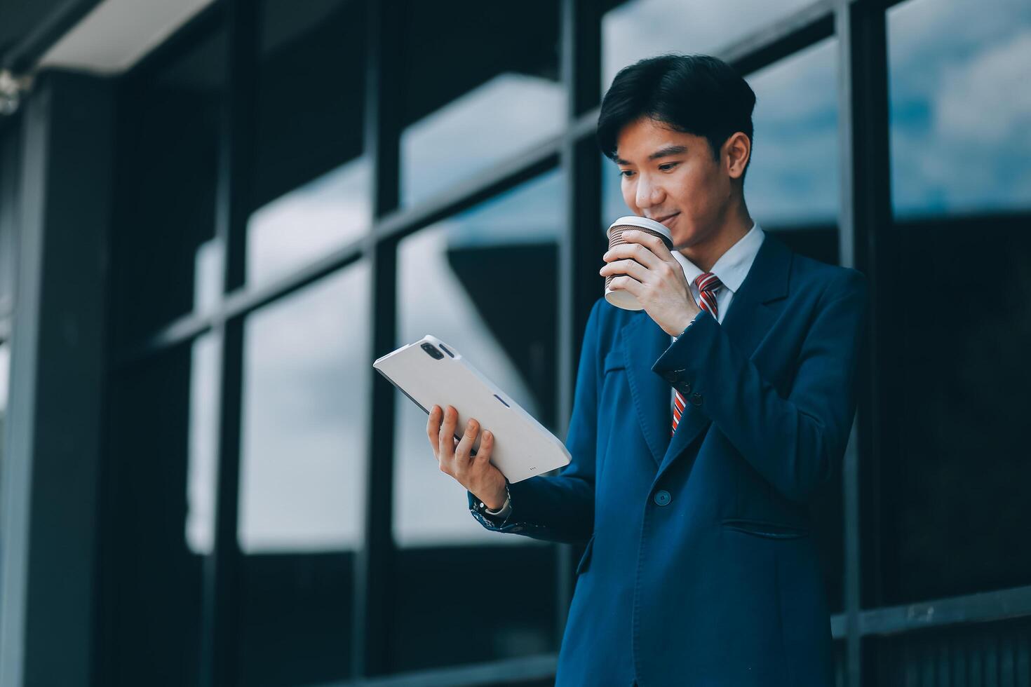 Businessman using tablet and enjoying in coffee break in front of the the corporation. Business, lifestyle concept photo