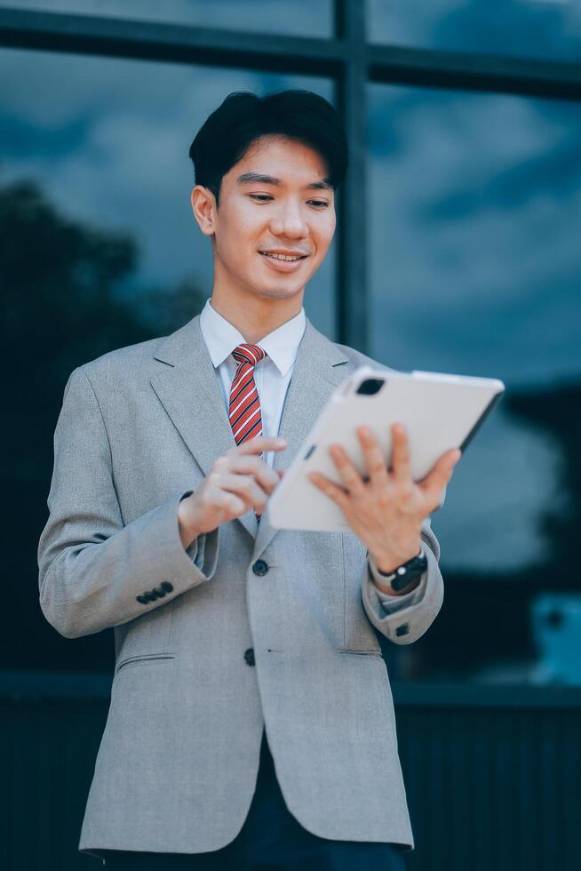 Serious businessman looking at paper documents in front of office building. Focused male manager checking reports before work while standing outdoors. photo