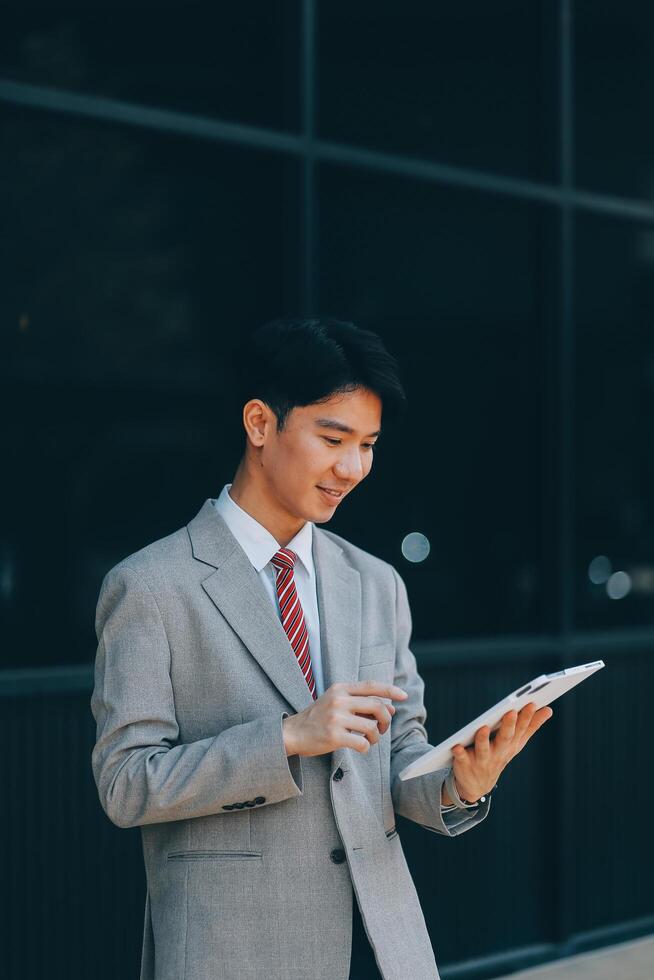 Serious businessman looking at paper documents in front of office building. Focused male manager checking reports before work while standing outdoors. photo