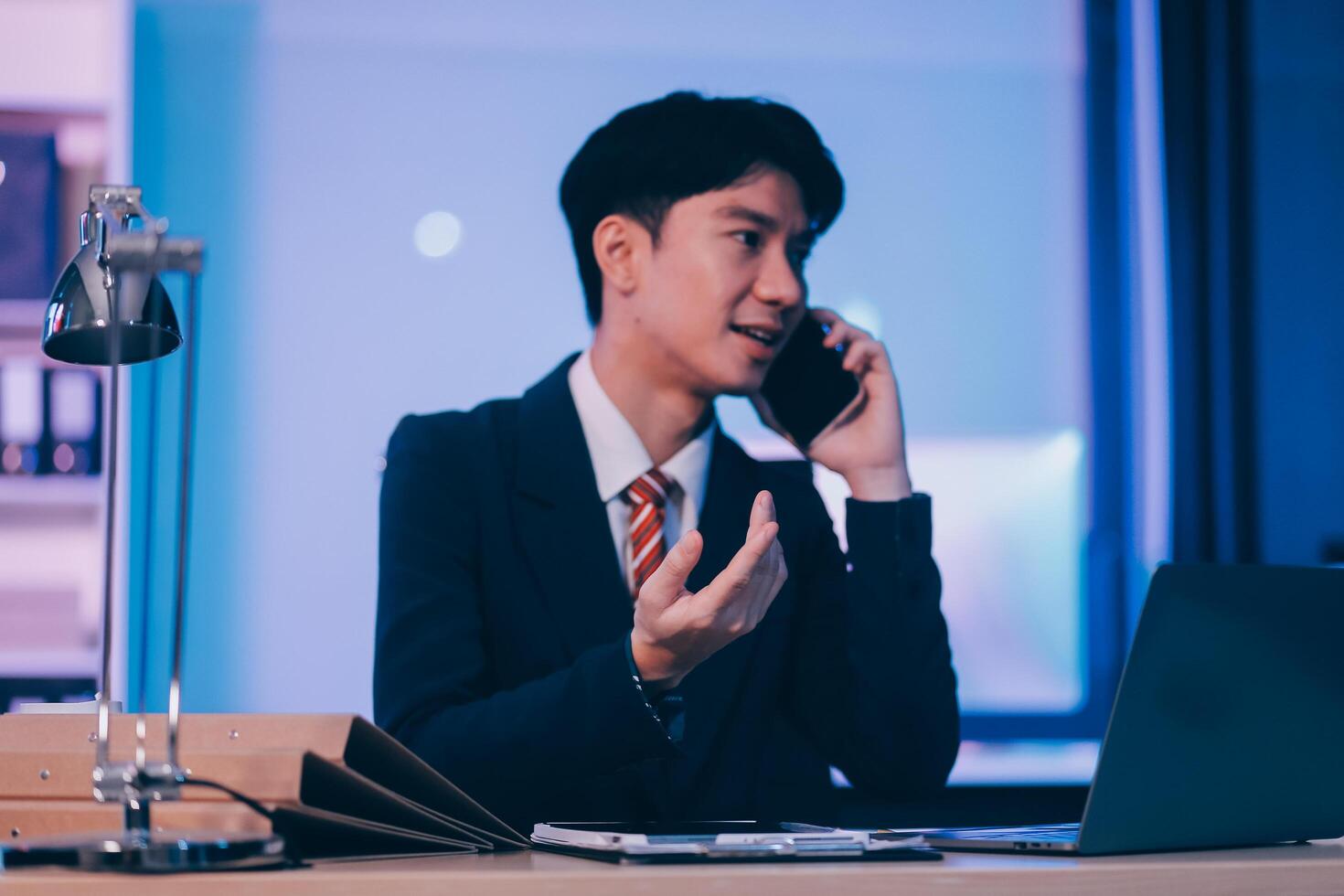 Serious trader using mobile phone app on smartphone for checking stock trading data analysis concept, focused businessman holding cellphone working in office with financial graph on computer monitors photo