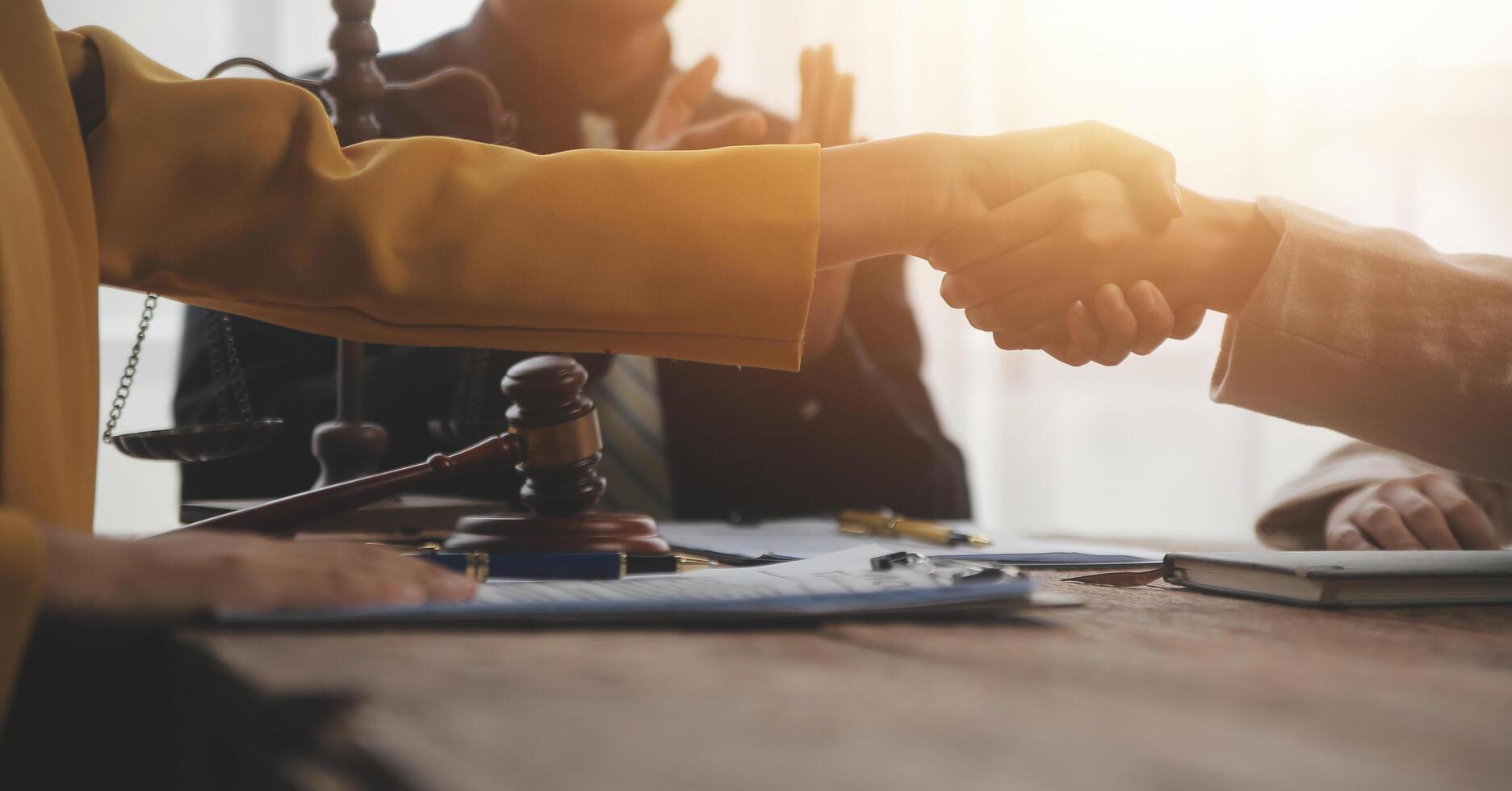 Lawyer shaking hands with a client making about documents, contracts, agreements, cooperation agreements with a female client at the lawyer's desk and a hammer at the table. photo