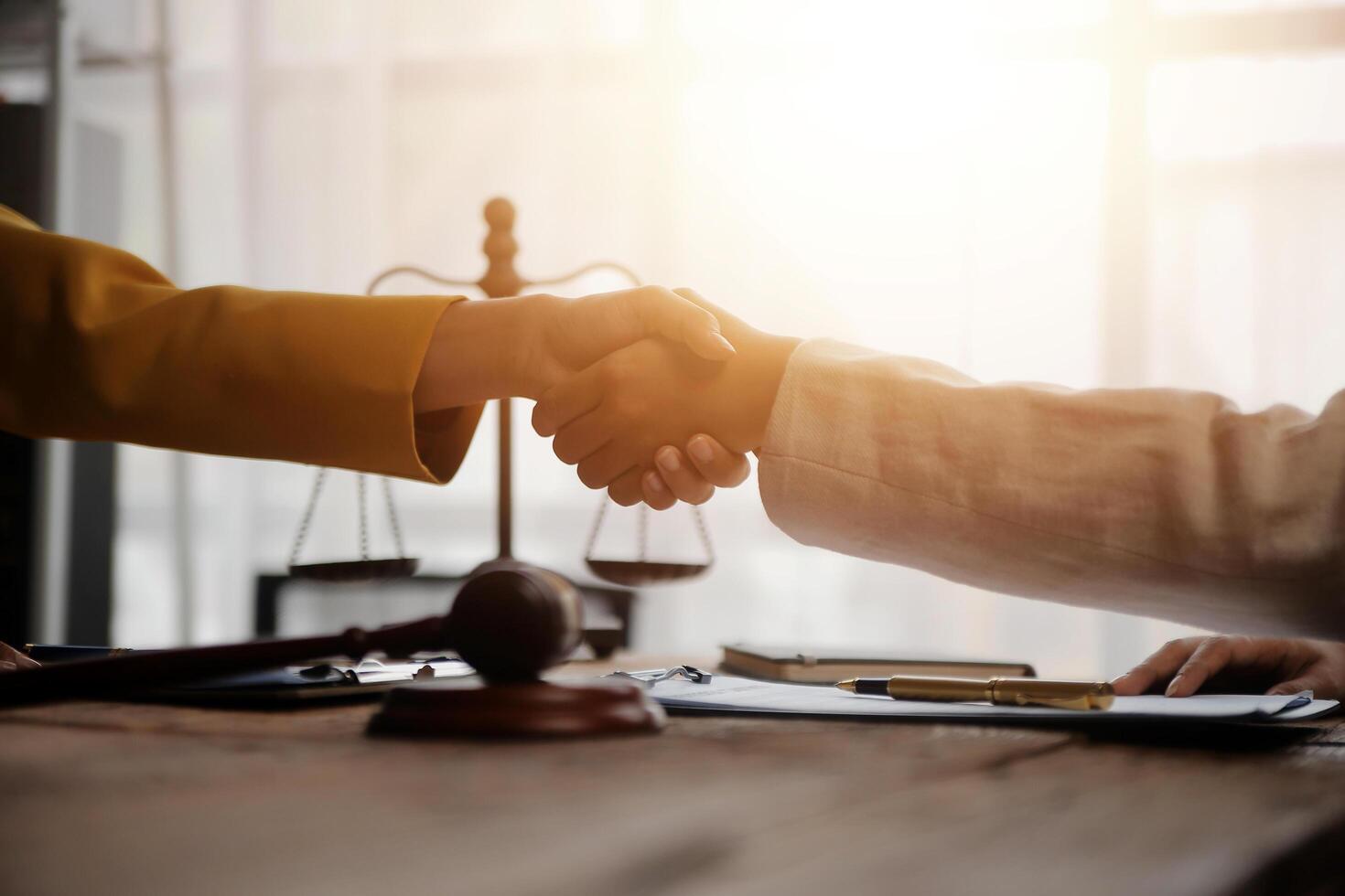 Lawyer shaking hands with a client making about documents, contracts, agreements, cooperation agreements with a female client at the lawyer's desk and a hammer at the table. photo