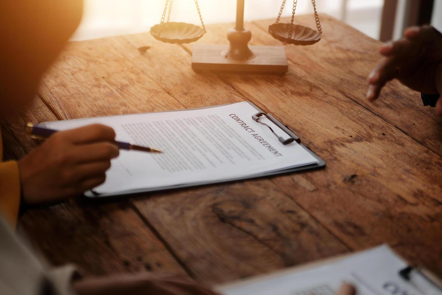 Business and lawyers discussing contract papers with brass scale on desk in office. Law, legal services, advice, justice and law concept picture with film grain effect photo