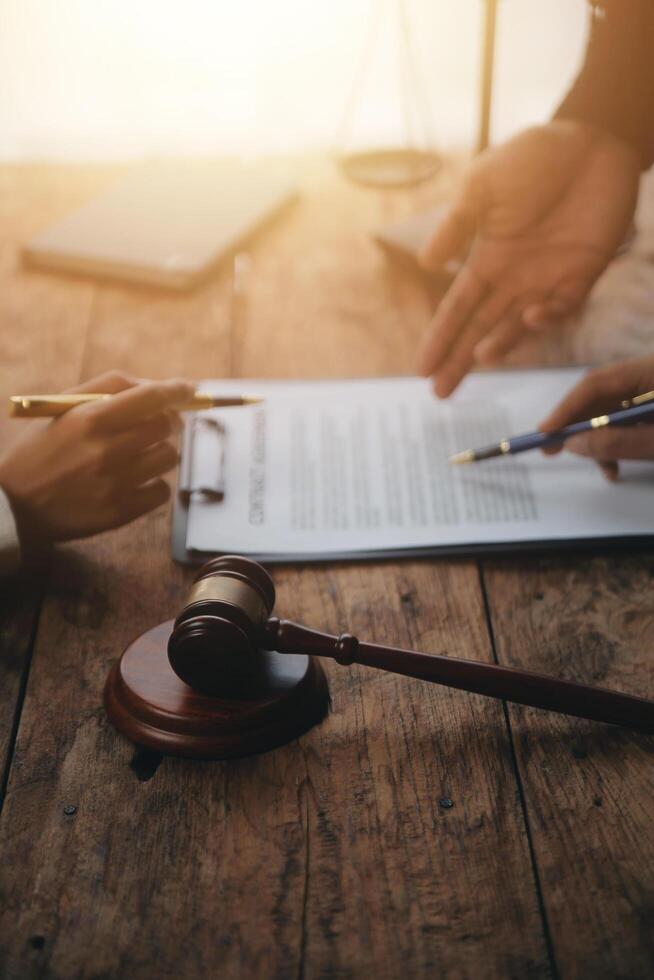 Business and lawyers discussing contract papers with brass scale on desk in office. Law, legal services, advice, justice and law concept picture with film grain effect photo