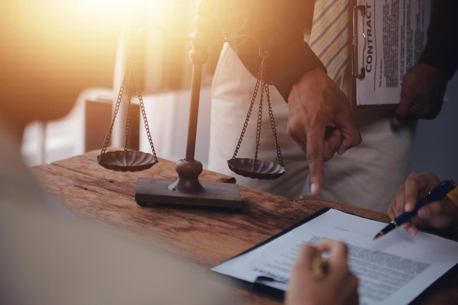 Business and lawyers discussing contract papers with brass scale on desk in office. Law, legal services, advice, justice and law concept picture with film grain effect photo