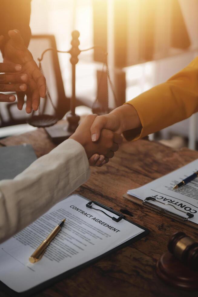 Lawyer shaking hands with a client making about documents, contracts, agreements, cooperation agreements with a female client at the lawyer's desk and a hammer at the table. photo