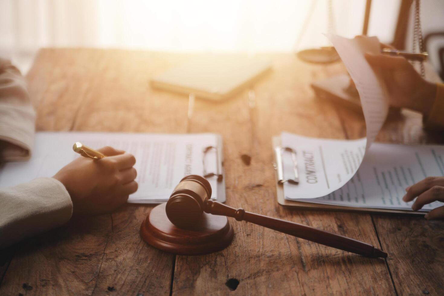Business and lawyers discussing contract papers with brass scale on desk in office. Law, legal services, advice, justice and law concept picture with film grain effect photo