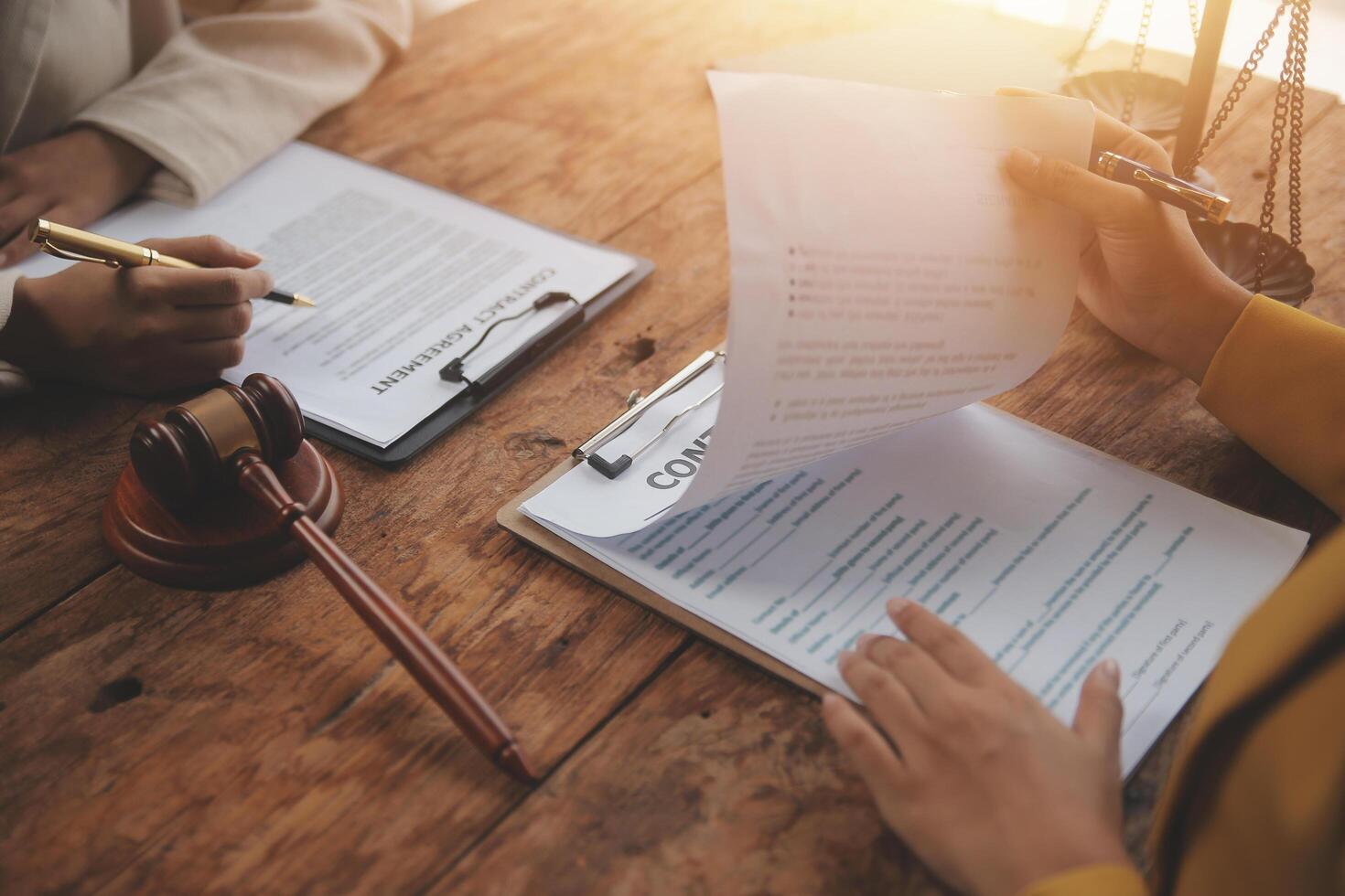 Business and lawyers discussing contract papers with brass scale on desk in office. Law, legal services, advice, justice and law concept picture with film grain effect photo