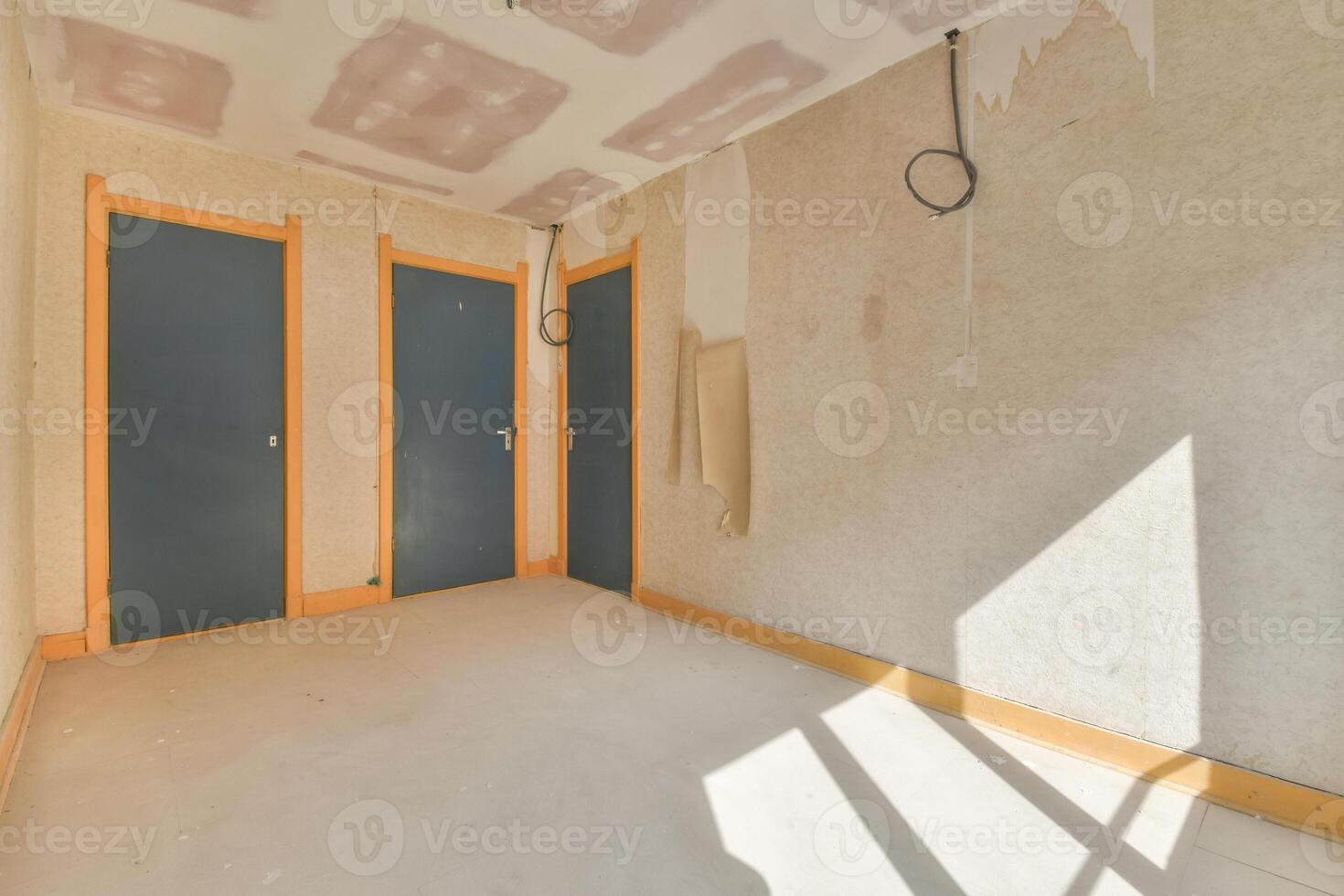 A room with two doors and a wall covered in drywall photo