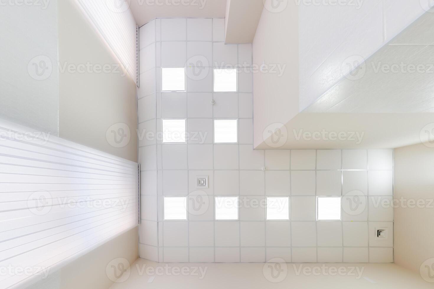 cassette stretched or suspended ceiling with square halogen spots lamps and drywall construction in empty room in house or office. Looking up view photo