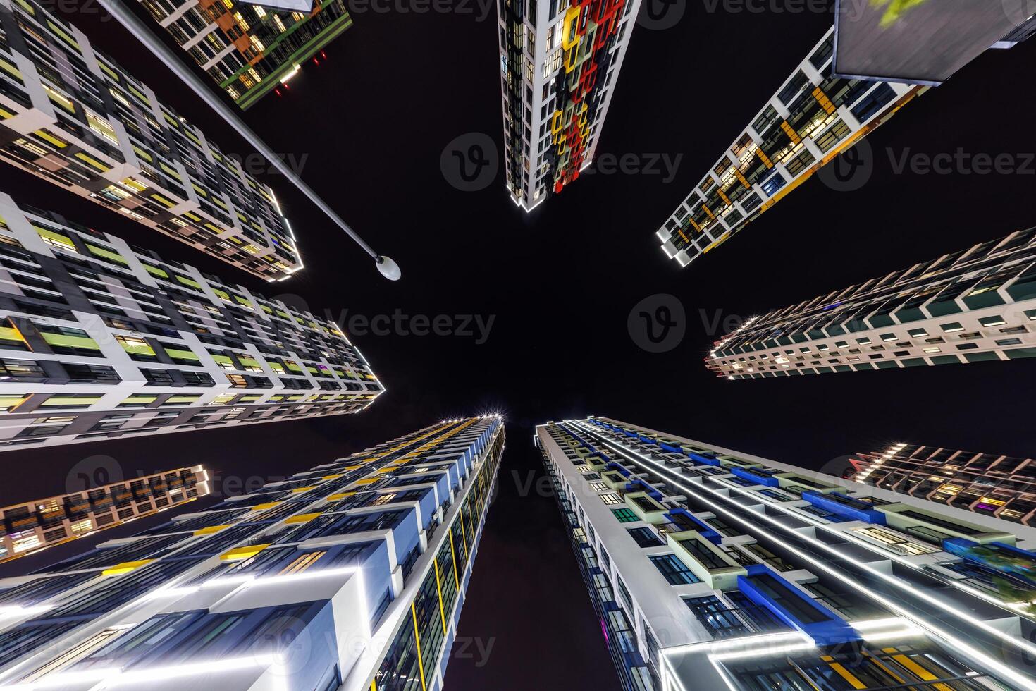 view from below into night sky of large modern skyscraper residential complex photo