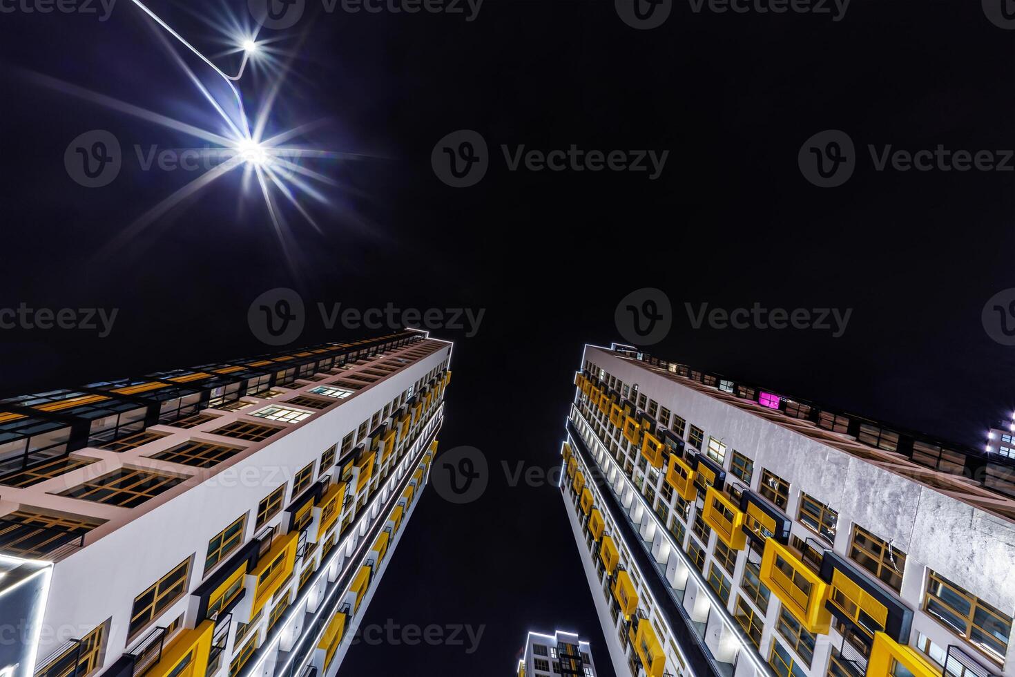 view from below into night sky of large modern skyscraper residential complex photo