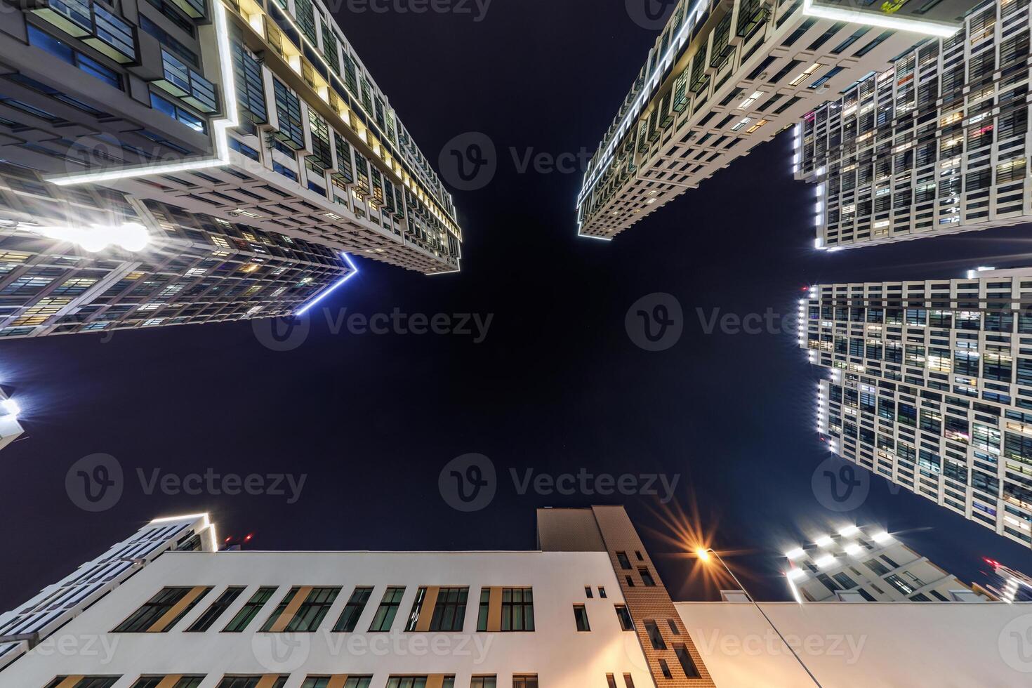 view from below into night sky of large modern skyscraper residential complex photo