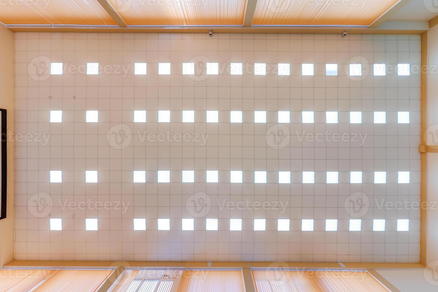 cassette stretched or suspended ceiling with square halogen spots lamps and drywall construction in empty room in house or office. Looking up view photo