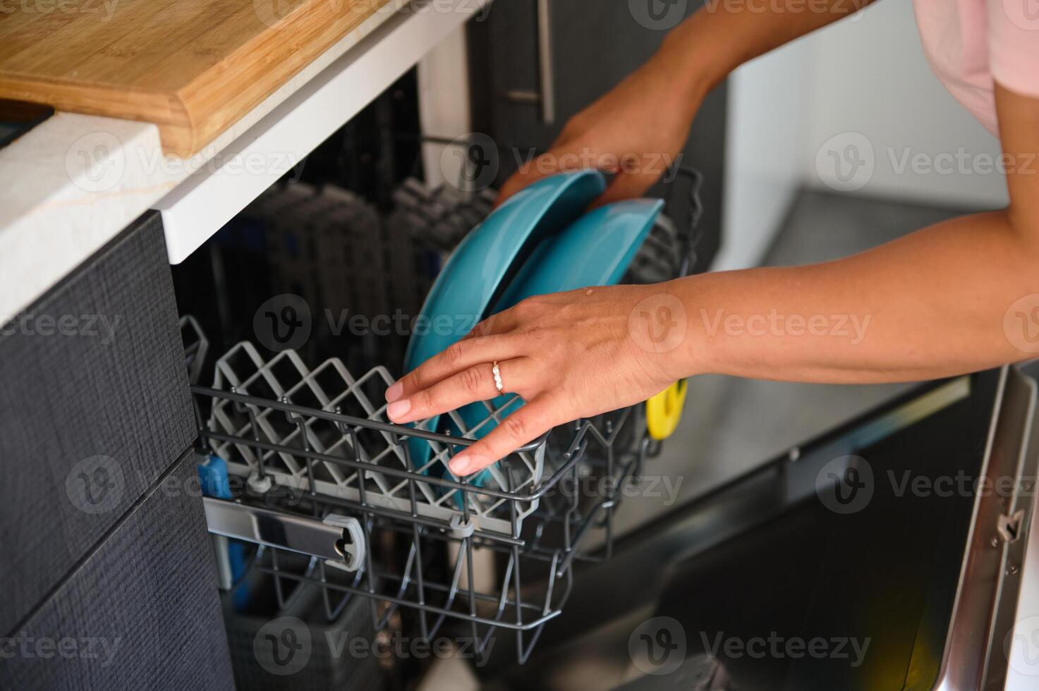 Person loading dishwasher with clean blue plates in modern kitchen, showcasing household chores and daily routine with focus on cleanliness and convenience photo