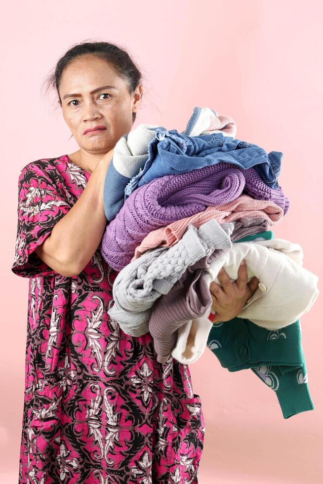 Asian Mom Weearing Daster Holding Wrinkled Clothes Laundry with Angry Face Expression photo