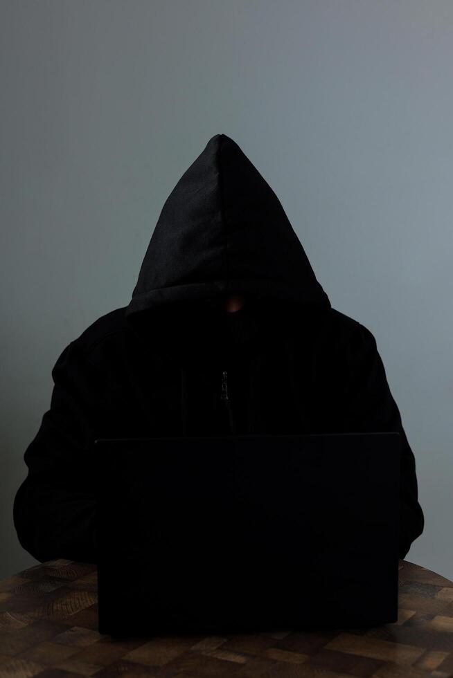 A Man Wearing Balaclava Sat Behind a Laptop photo
