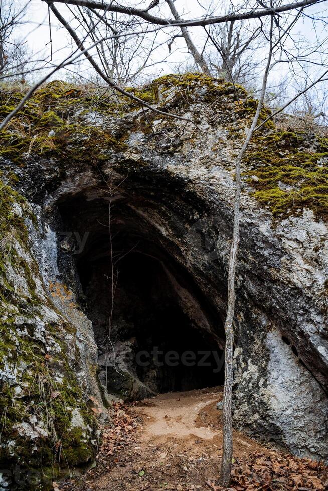 Entrance to a small cave, sandy floor in a karst sinkhole, natural object, Tourist route. photo