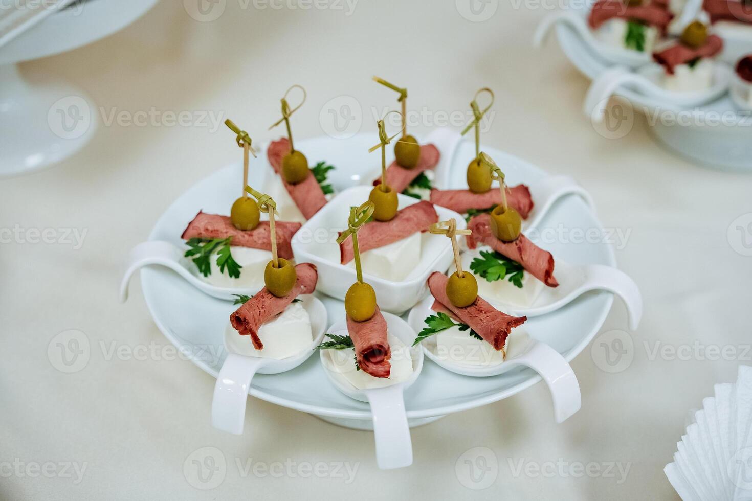 Appetizer on a plate, table setting for an event, ham and cheese on a skewer, pitted olive, catering for departure, beautiful serving of the dish. photo