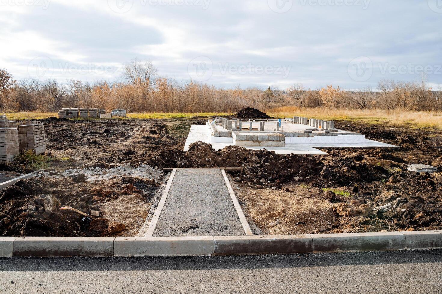 suburban construction, view of the construction of the house, concrete foundation, pillow of the foundation of the house, asphalt on the road, excavated earth. photo