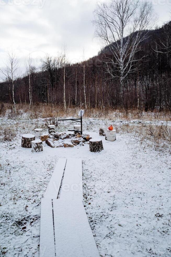 Winter landscape on a tourist meadow, camping covered with snow, winter atmosphere in the forest, parking for tourists with tents, campfire site. photo