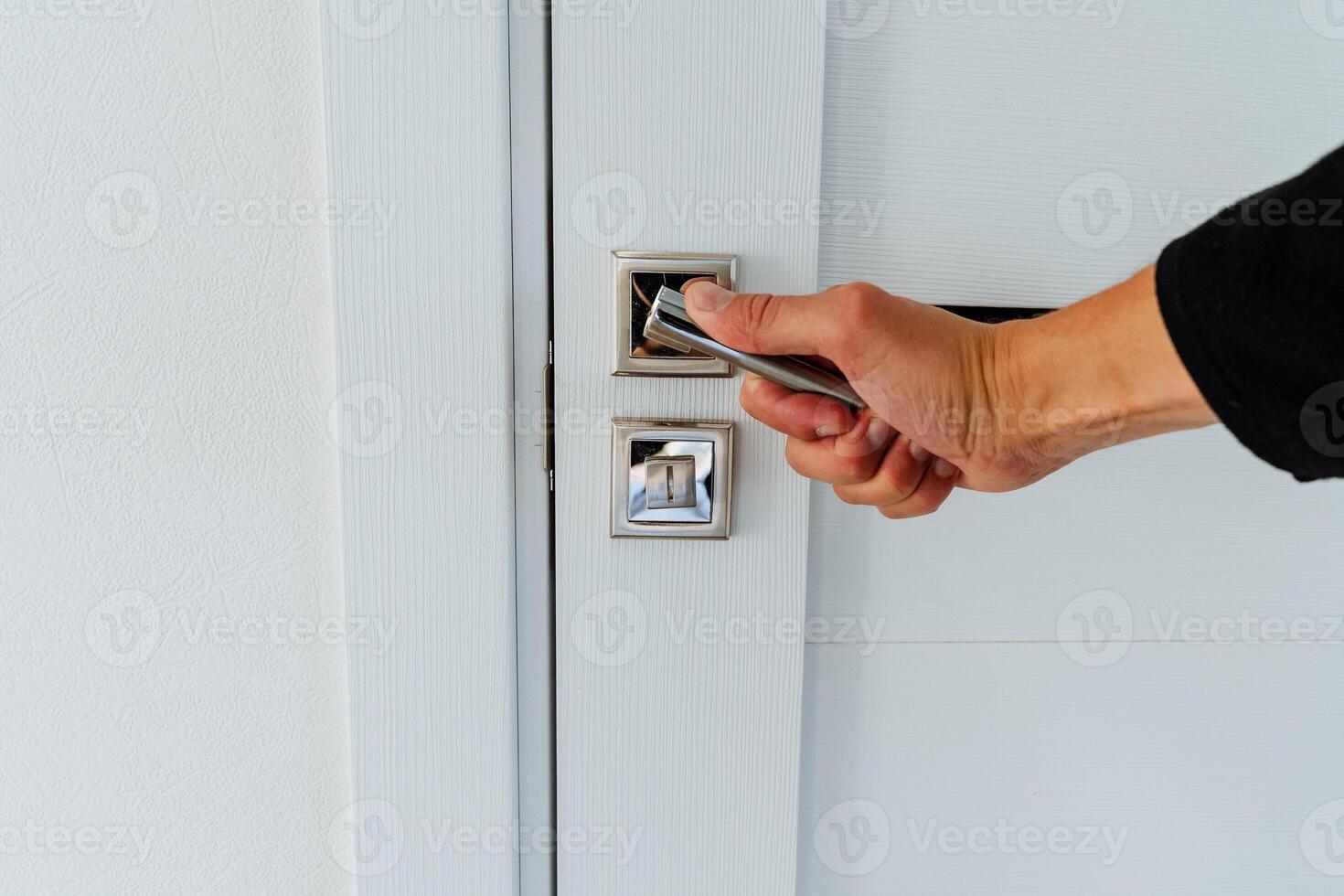 Opening the door in the room, hand opening the door by the handle, chrome door lock elements. photo