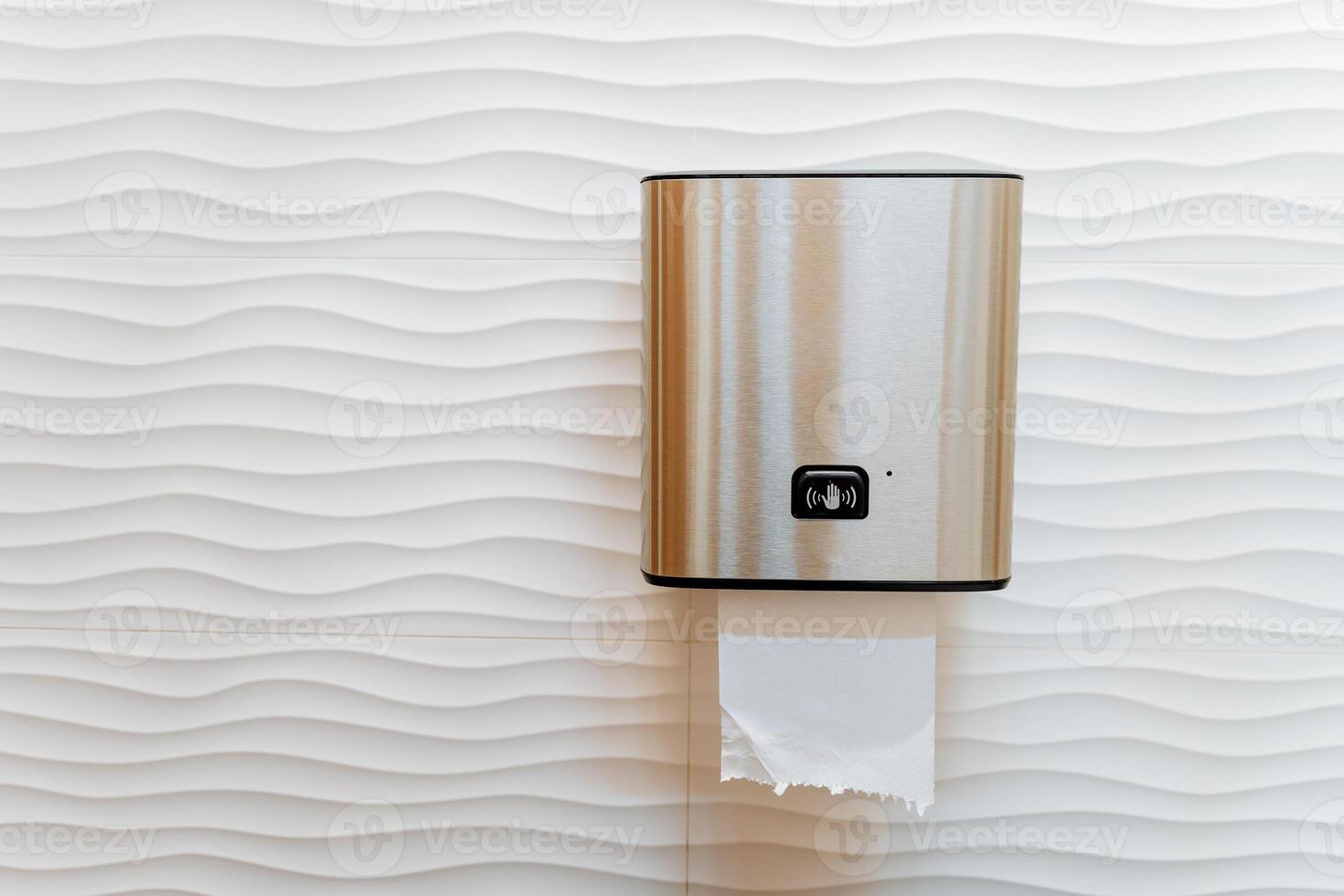 Automatic paper towel dispenser, piece of paper sticking out of the dispenser in the toilet, paper dispenser, clean hands, cleaning machine. photo
