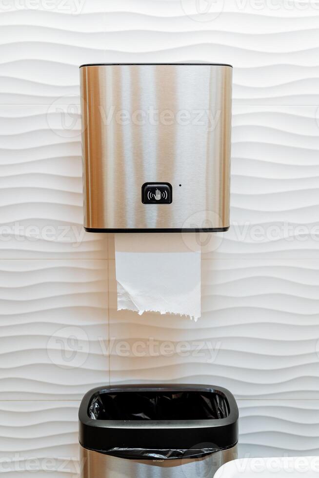 Automatic paper feeding in the dispenser, toilet room, paper towel dispenser, hand wave sensor, portion dispenser, garbage can. photo
