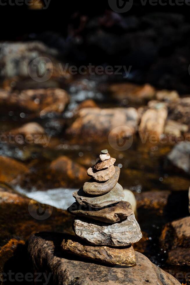 A pyramid of stones on the river, flat stones lie in a stack in the bed of a mountain river, a balance in nature, a tour, a slide of cobblestones. photo