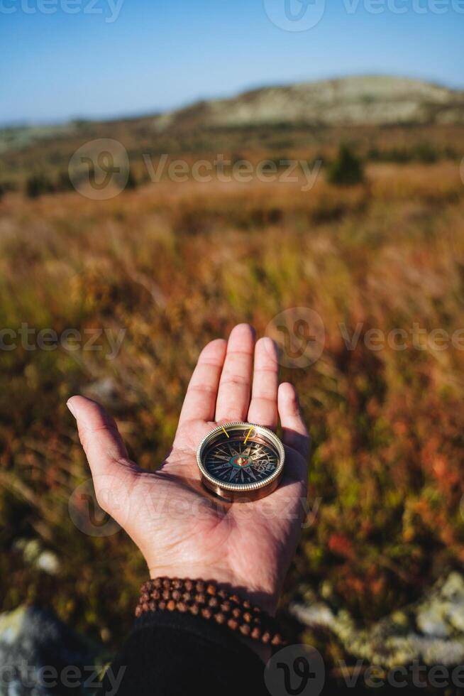 A compass lies in the hand of a young man, orienteering on the ground, a magnetic arrow points north, navigation in the forest, a person is lost. photo