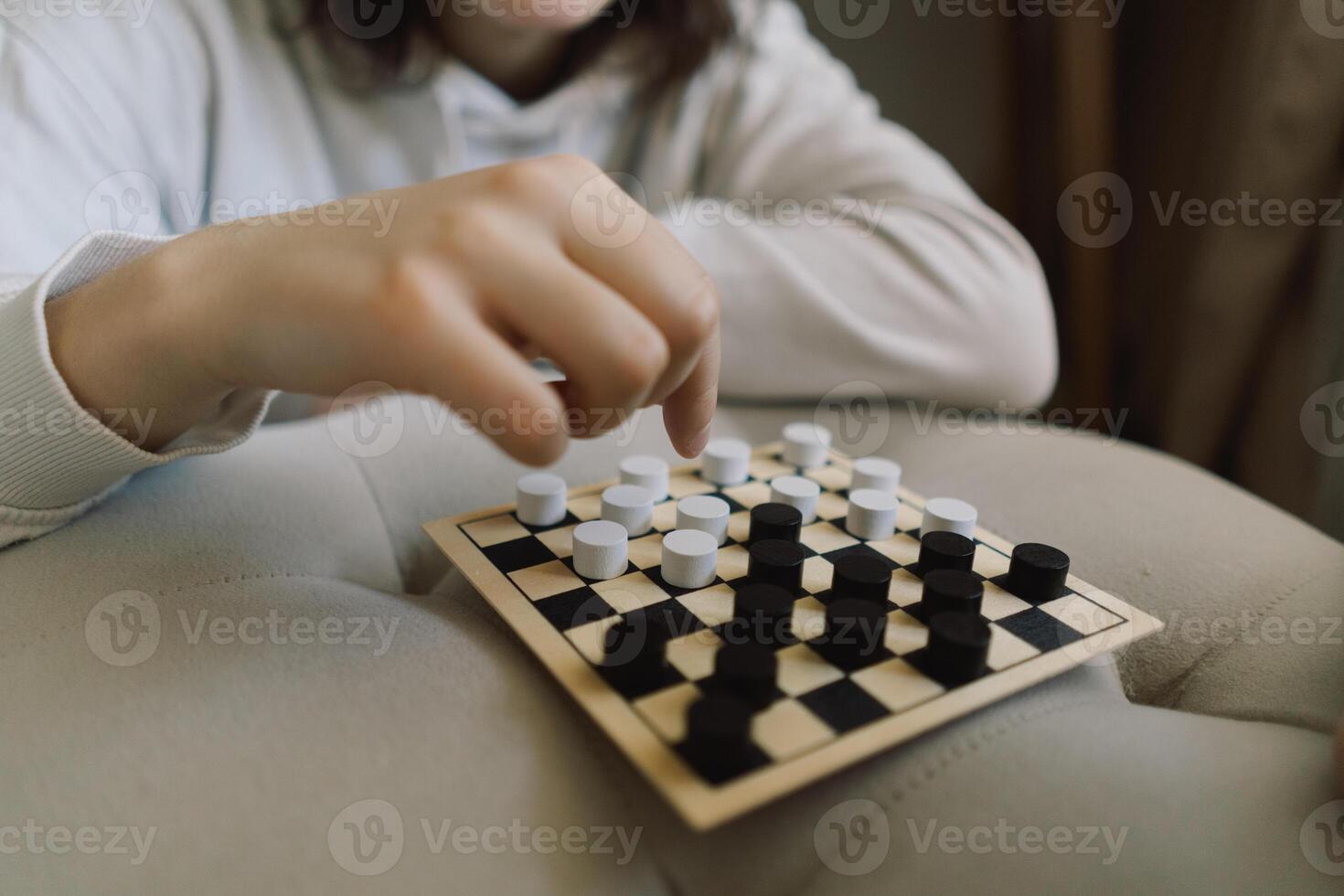 Teenage Girl and Boy Playing Board Game checkers In Living Room photo