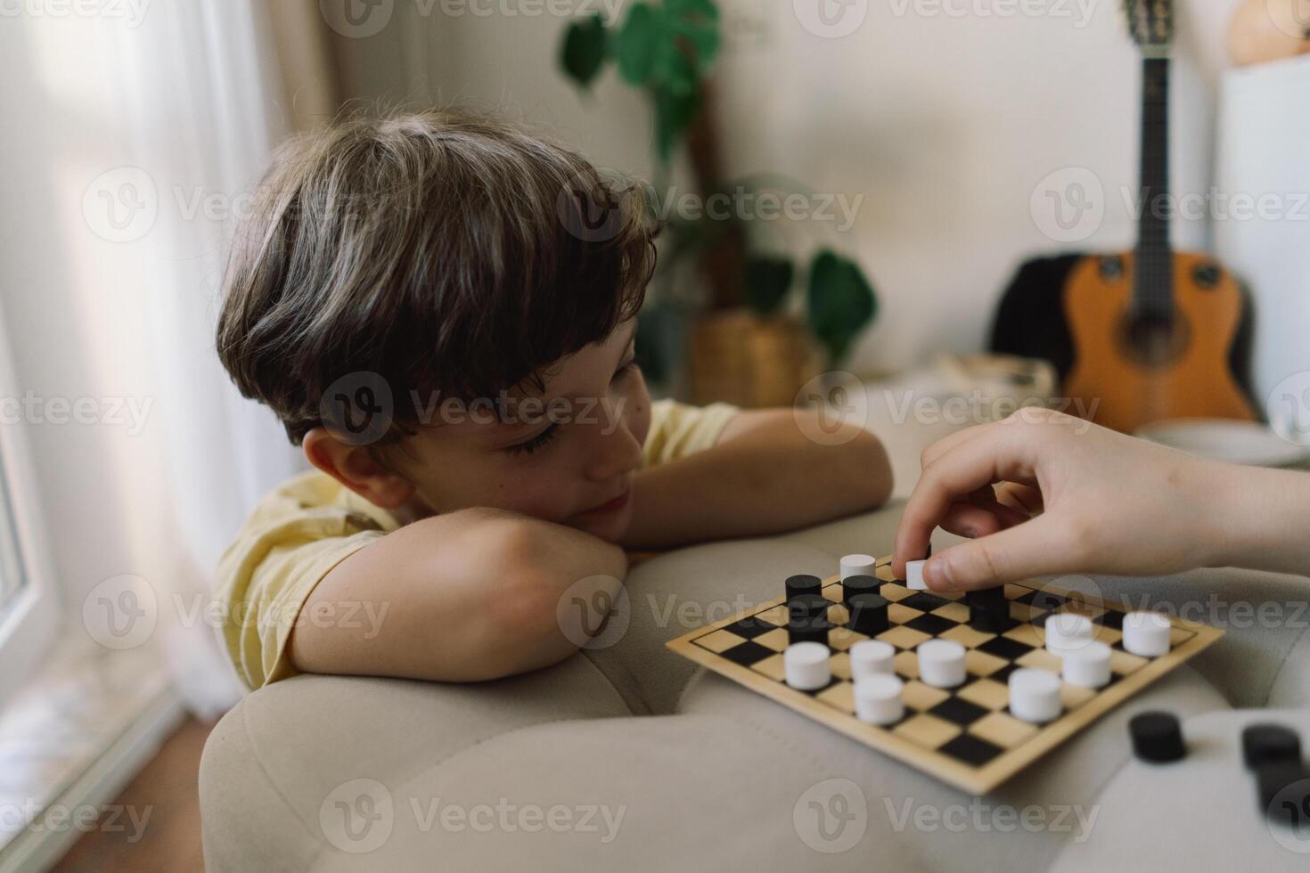 Teenage Girl and Boy Playing Board Game checkers In Living Room photo