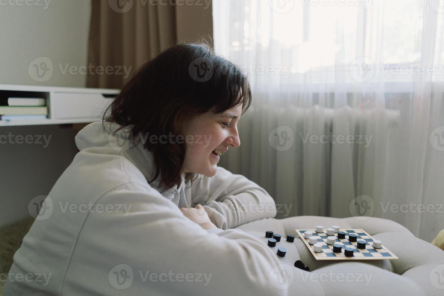 Teenage Girl and Boy Playing Board Game checkers In Living Room photo