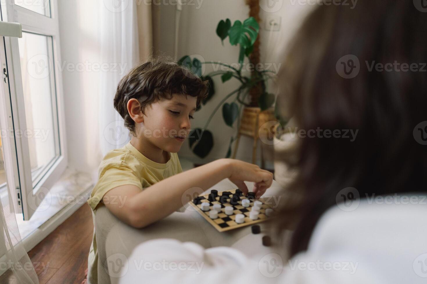 Teenage Girl and Boy Playing Board Game checkers In Living Room photo