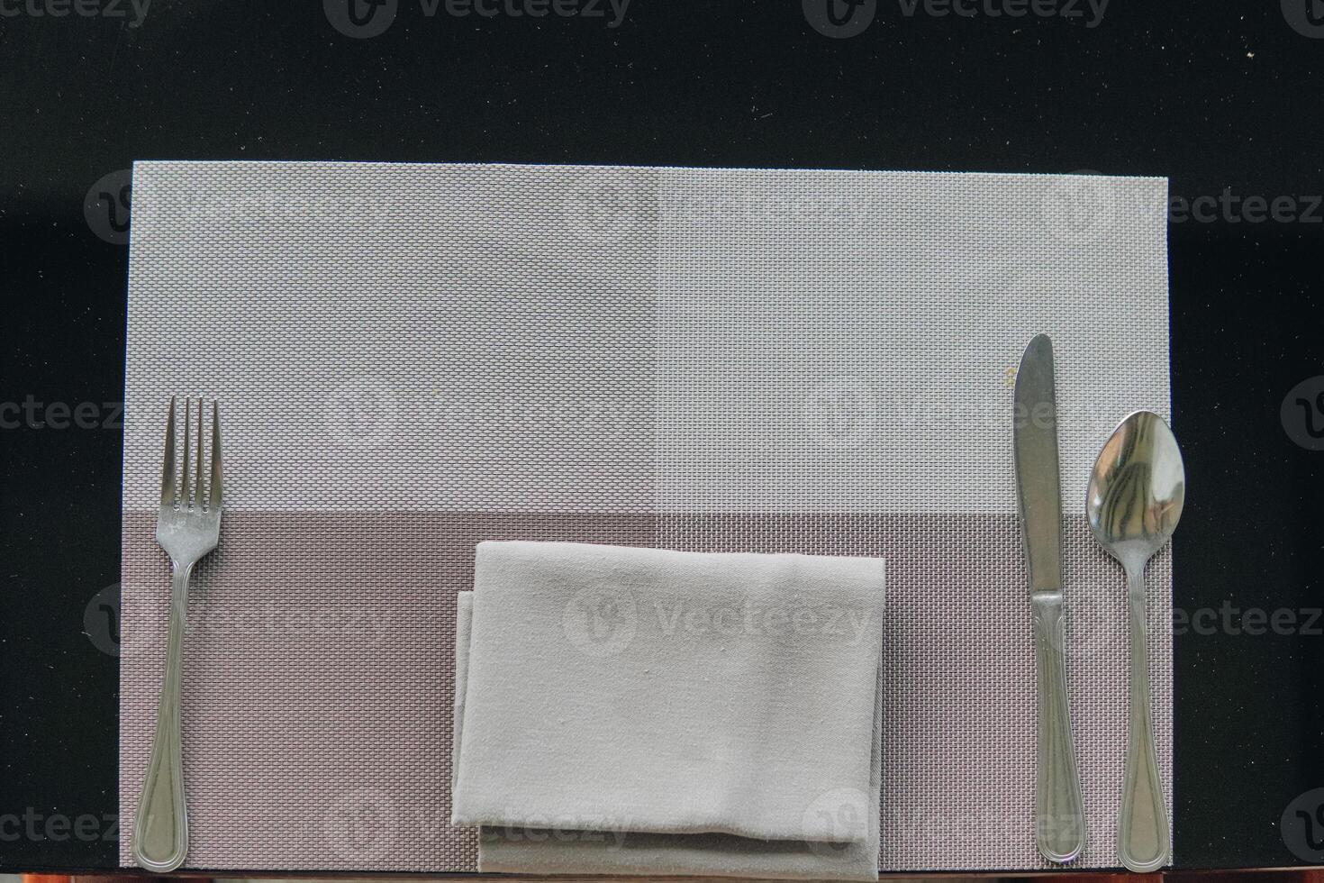 A silverware set is placed on a table with a napkin, set for a meal. photo