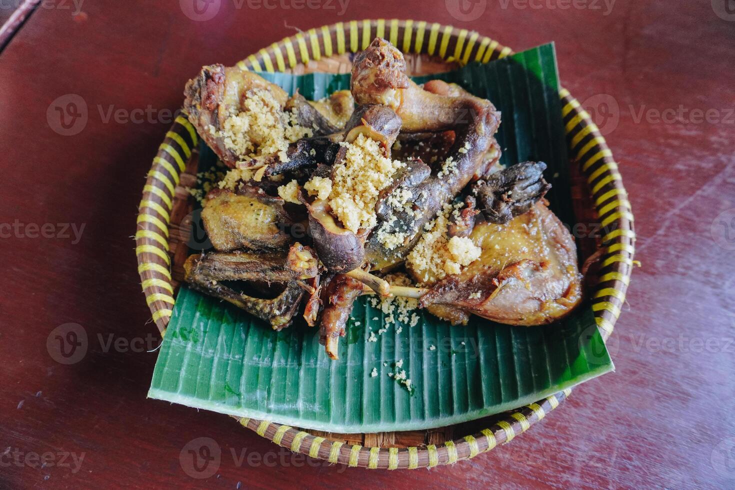 Traditional fried chicken with a yellow crispy condiment served on top of banana leaf. photo