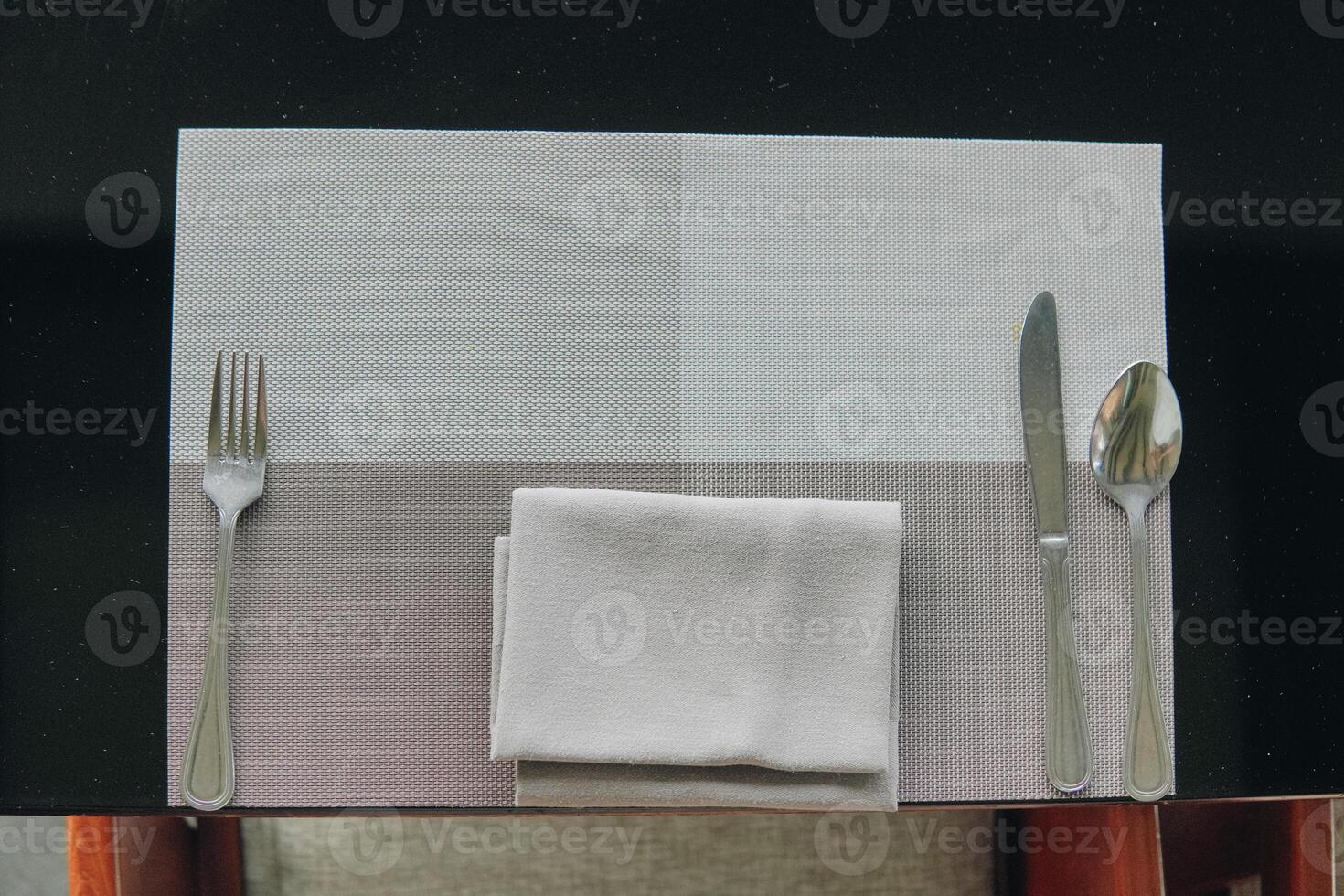A silverware set is placed on a table with a napkin, set for a meal. photo