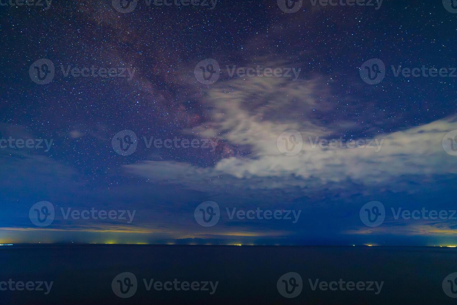 starry night sky over large mountain lake at night photo