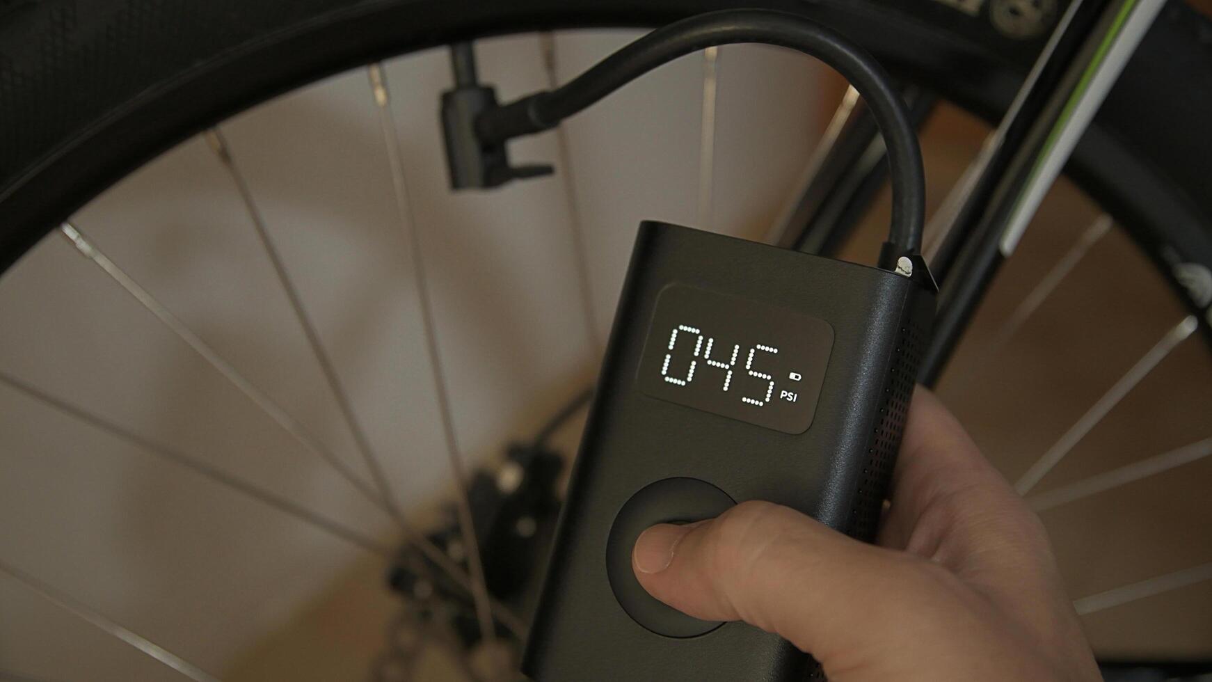 Man using cordless portable air pump inflating bicycle tire photo