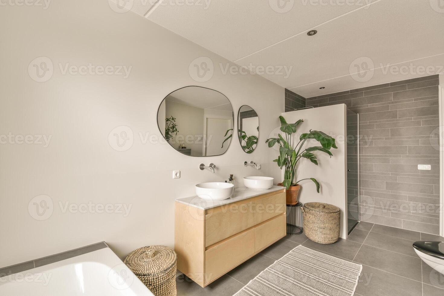 A bathroom with a white sink and a wooden vanity photo