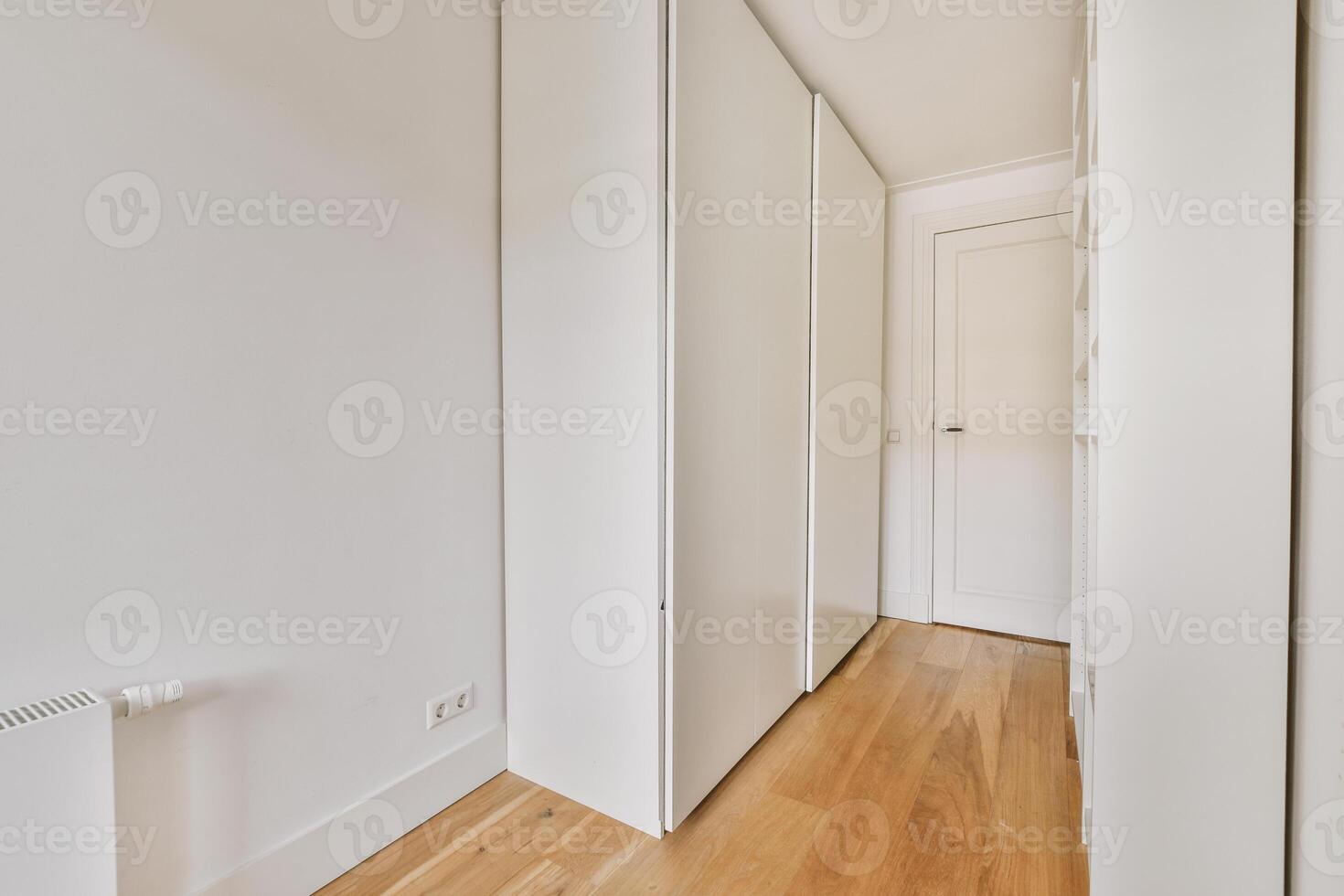 A hallway with white walls and wooden floors photo