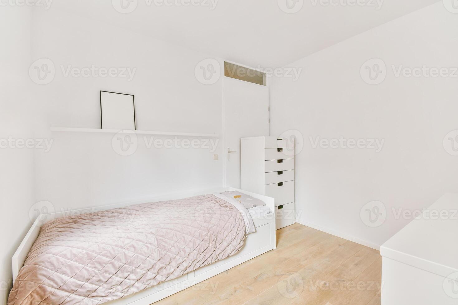 A bedroom with a bed, dresser and a white wall photo