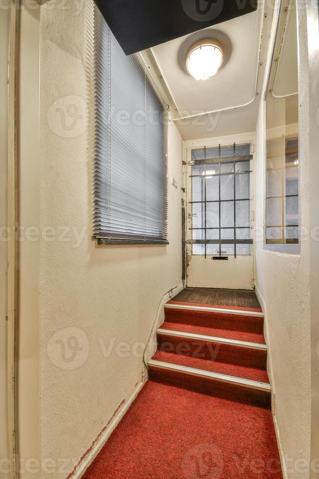 A hallway with a red carpet and stairs photo