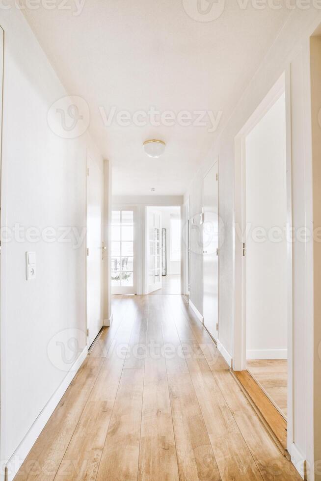 A long hallway with white walls and wooden floors photo